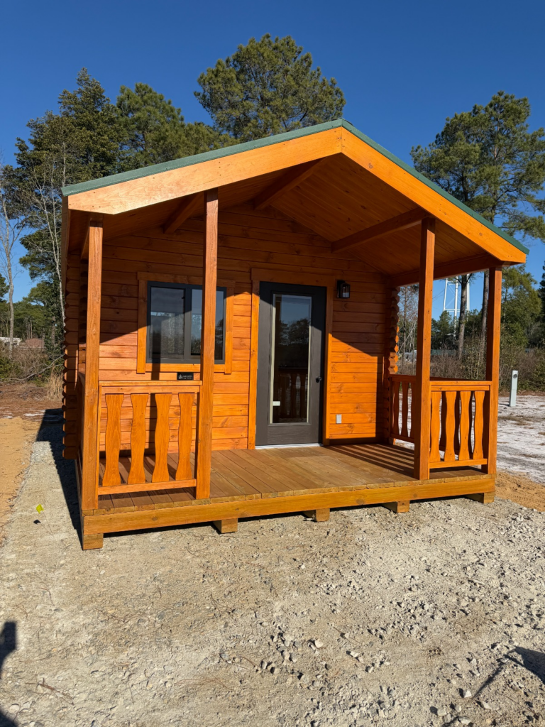 A charming wooden cabin with a porch, surrounded by trees, perfect for a cozy getaway in nature.