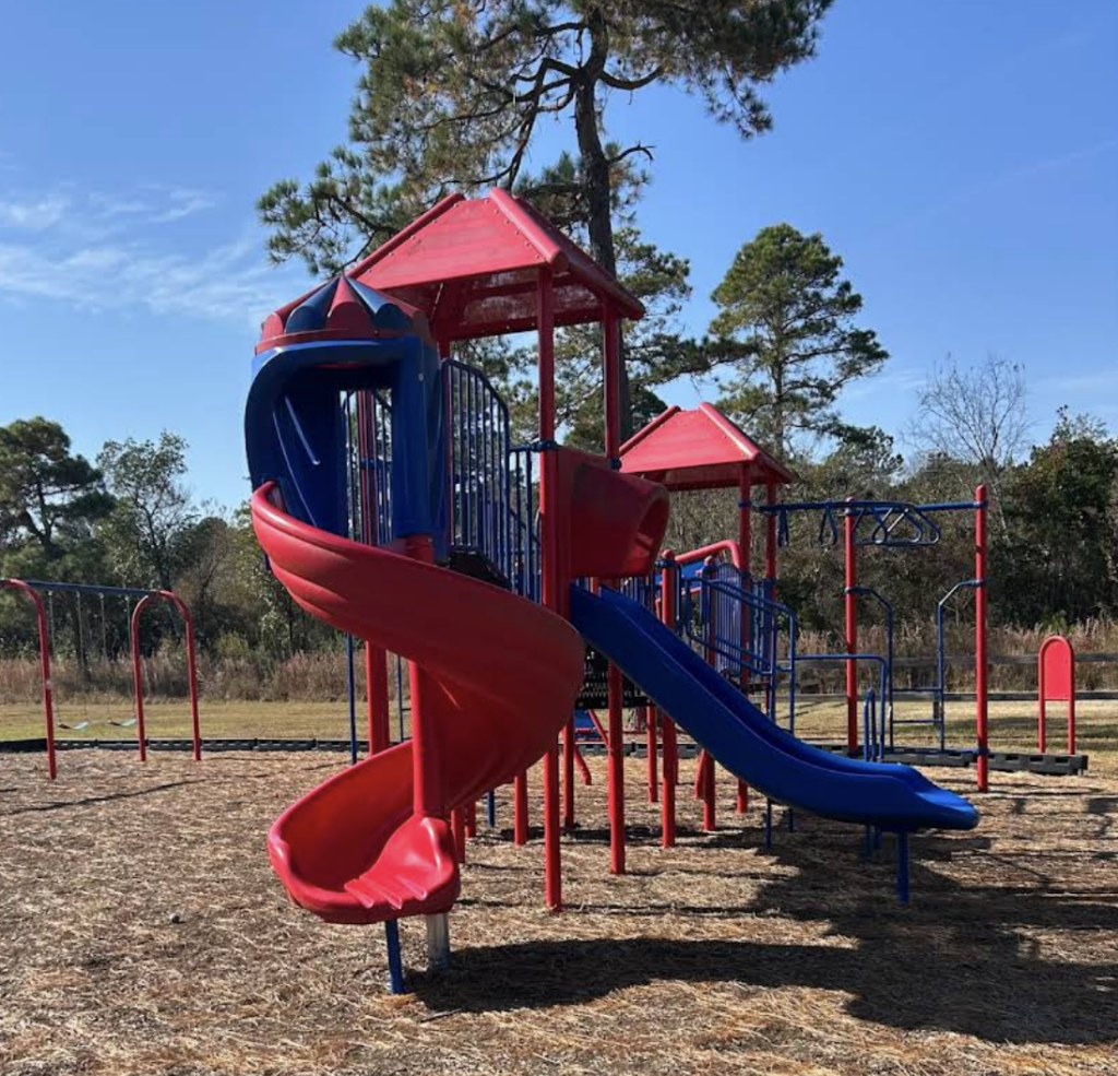 Colorful playground equipment featuring slides and climbing structures under a clear blue sky.