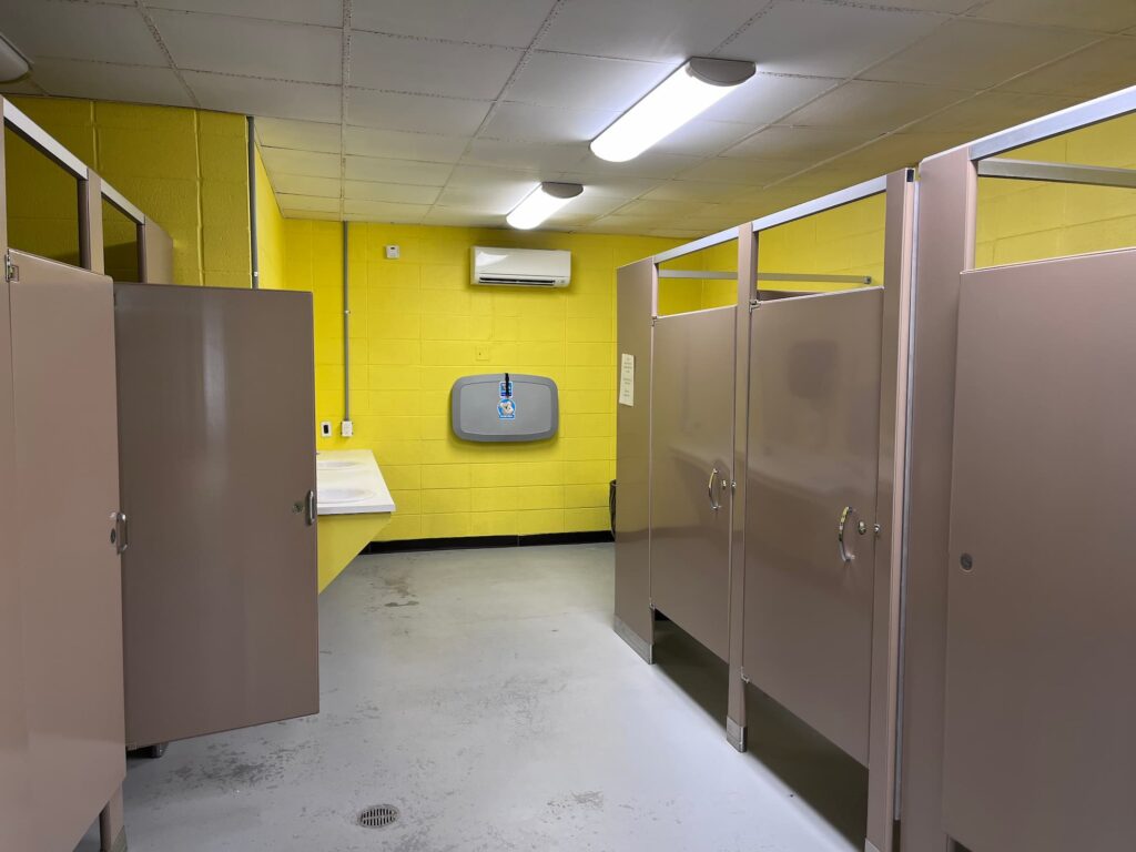 Clean and modern restroom interior featuring yellow walls, privacy stalls, and a hand dryer for convenience.