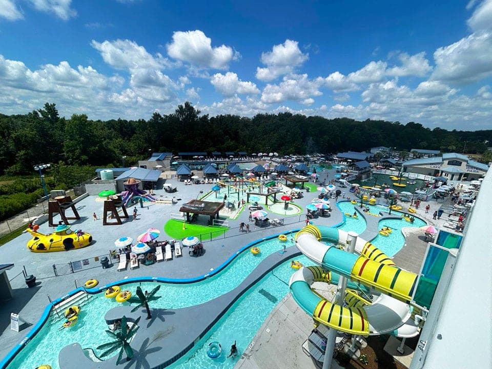 Aerial view of a vibrant water park featuring slides, pools, and colorful umbrellas on a sunny day.